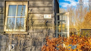 A rustic wooden cabin with a window and a door, surrounded by autumn foliage. - Tranquil Holiday Home in Lage Zwaluwe With Terrace (Lage Zwaluwe)