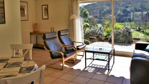 A living room with two leather chairs, a glass table, a sofa, and a view of a garden through a sliding glass door. - Spacious Holiday Home on Estate Near Covas (Tábua)
