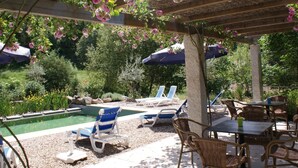 A poolside area with lounge chairs, a table, and umbrellas under a pergola with flowering vines. - Spacious Holiday Home on Estate Near Covas (Tábua)