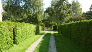 A paved pathway flanked by neatly trimmed hedges, leading towards a gate. - Modernly Furnished Holiday Home Near the Beach (Rostock)