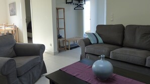 A living room with two grey sofas, a wooden ladder, a small table with a vase, and a bench. - Modernly Furnished Holiday Home Near the Beach (Rostock)