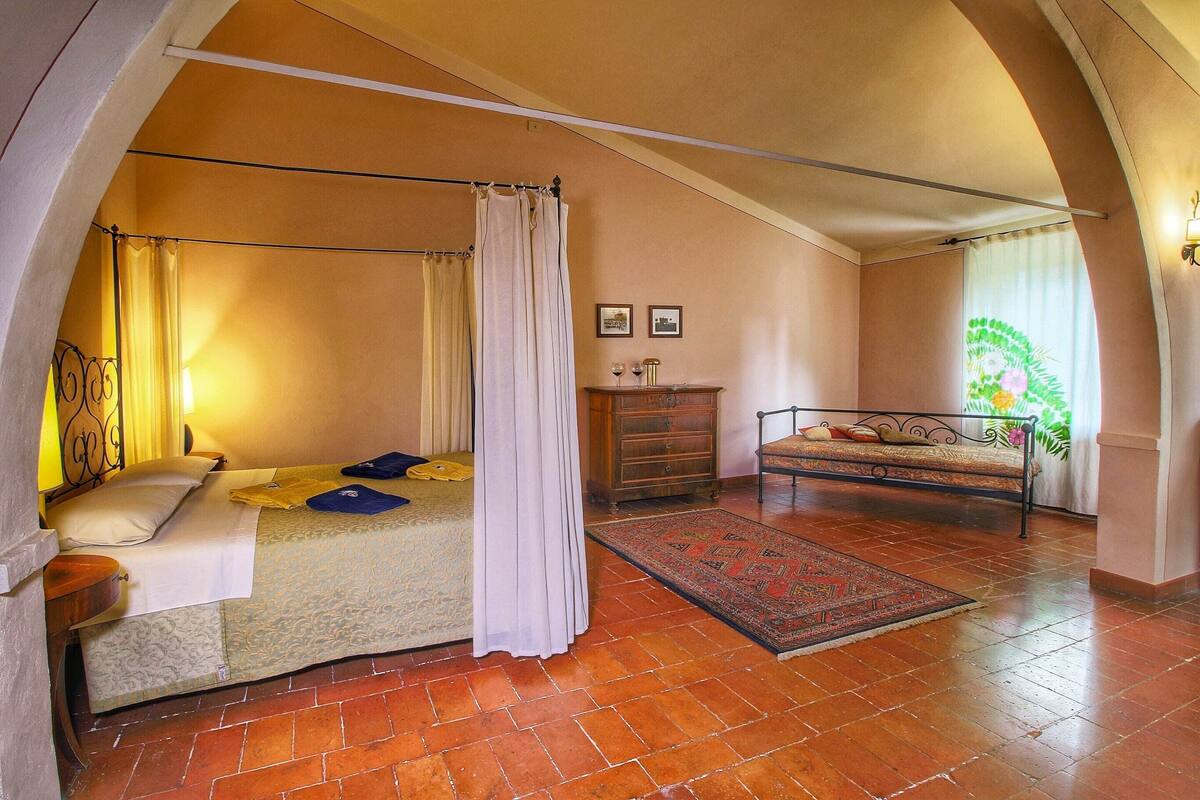 Une chambre à coucher comprenant un lit, une table de chevet, une commode, une fenêtre avec des rideaux et un tapis à motifs.