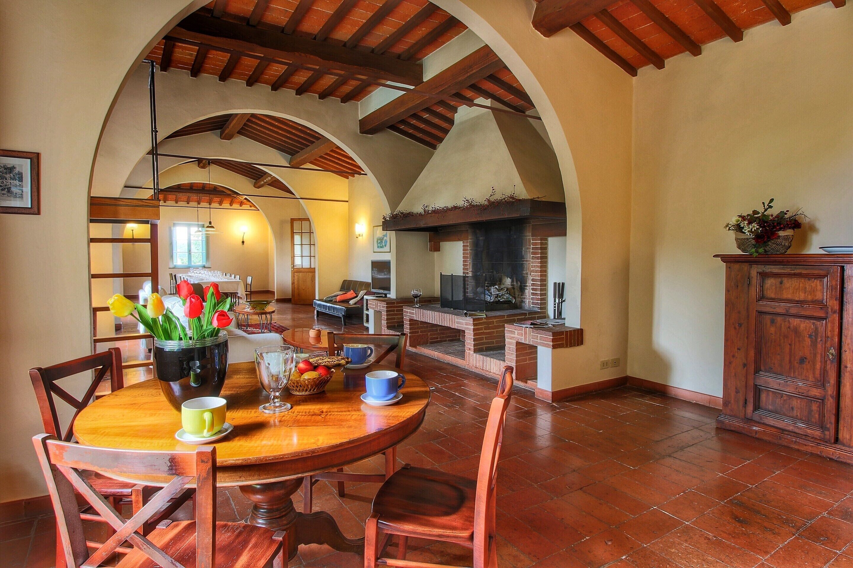A dining area with a round wooden table, chairs, and a fireplace.