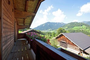 Un balcone in legno con vista su colline verdi e cielo sereno.