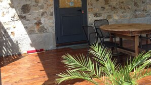 A stone wall exterior with a wooden door, a round wooden table, and metal chairs. - Charming Residence in the Hills Surrounding La Spezia (Bolano)