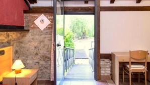 A room with a bed, a desk, a chair, a lamp, and a door leading to an outdoor area. - Charming Residence in the Hills Surrounding La Spezia (Bolano)