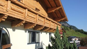 Eine Holzhütte mit geneigtem Dach, mehreren Fenstern und einem Balkon.