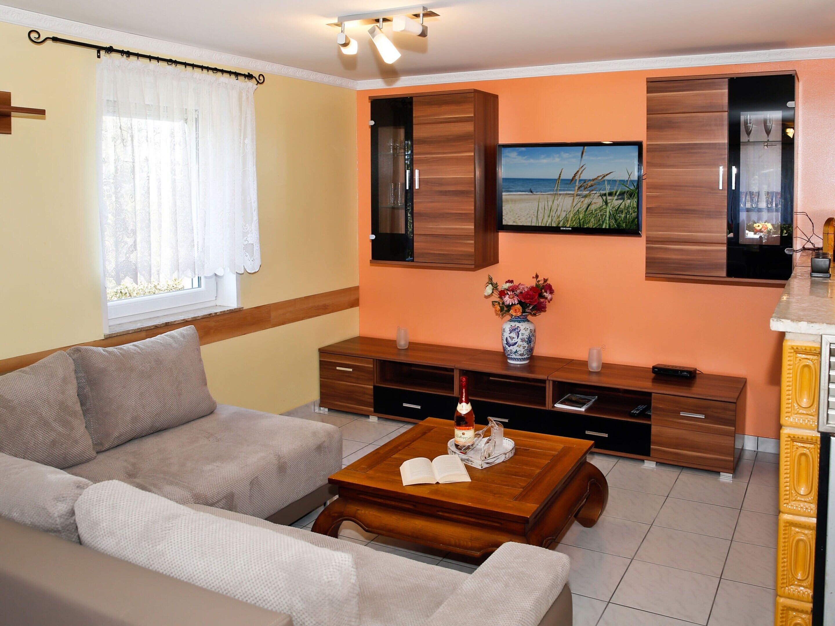 A living room with a sofa, coffee table, TV, wooden cabinets, and a window with curtains.