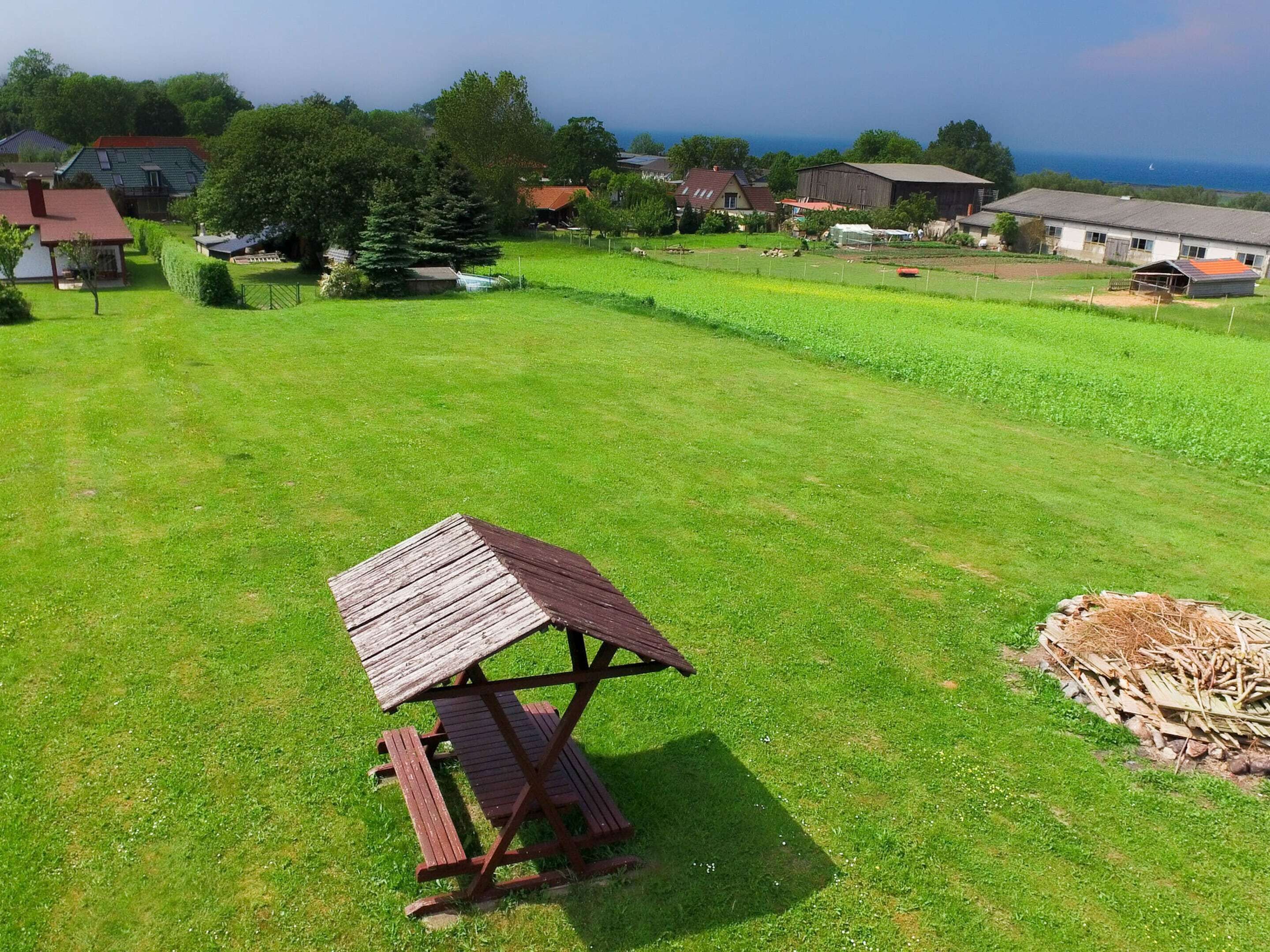 A picnic table in a grassy field with houses in the background.