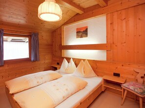 A wooden cabin room with a bed, a bench, and a window with curtains. - Alluring Apartment With Swimming Pool in Waidring Tyrol (Waidring)