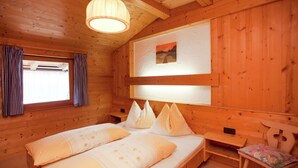 Una habitación tipo cabaña de madera con una cama, un banco y una mesita.