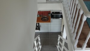 Eine Treppe führt zu einer Küche mit weißen Geländern und Holzboden.