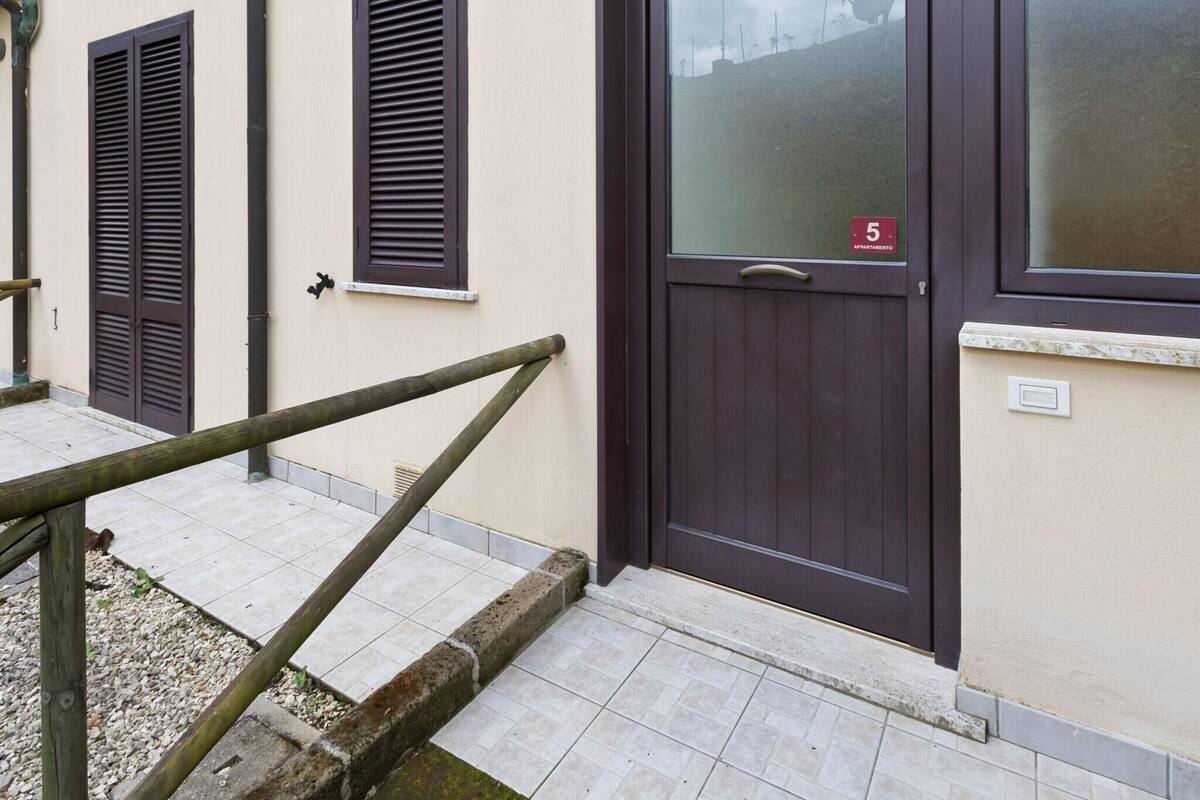Un bâtiment avec une porte de couleur brun foncé, une fenêtre avec des volets et une petite enseigne indiquant le numéro 5.