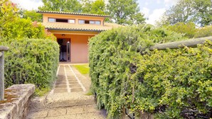A pathway leading to a two-story building with a tiled roof and a small balcony. - Gorgeous Holiday Home in Sorano With Swimming Pool (Sorano)