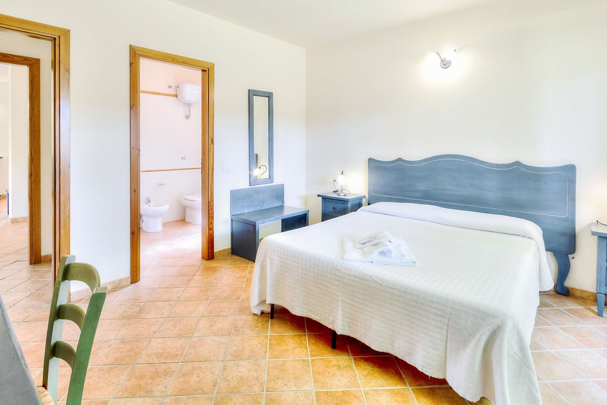 Une chambre à coucher avec un lit, des tables de chevet, un miroir et une vue sur la salle de bain.