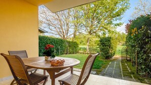 A patio with a round table and four chairs, a small basket, and a potted plant with red flowers. - Gorgeous Holiday Home in Sorano With Swimming Pool (Sorano)