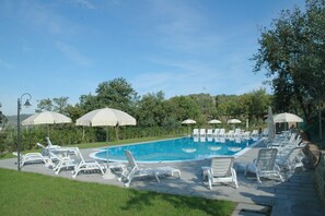 A swimming pool with lounge chairs and umbrellas, surrounded by greenery. - Air-conditioned Flat With Pool and Wellness Area (Citta della Pieve)