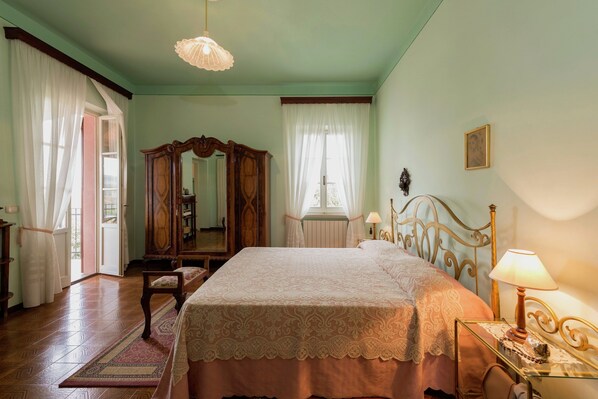 A bedroom with a large bed, a wooden wardrobe, a mirror, and a chandelier. - Air-conditioned Flat With Pool and Wellness Area (Citta della Pieve)