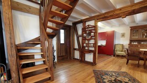 A spacious room with a wooden staircase, a red cabinet, and a patterned rug.