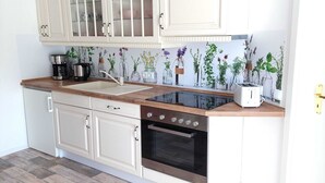 A kitchen with white cabinetry, a black stove, a sink, and a countertop with a coffee maker and a toaster. - Holiday Home in Idyllic Ziesar Near the Natuurpark (Ziesar)