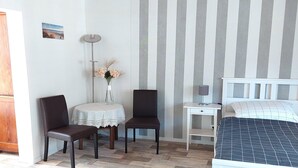 A bedroom with a bed, two chairs, a small table with a vase, and a nightstand. - Holiday Home in Idyllic Ziesar Near the Natuurpark (Ziesar)
