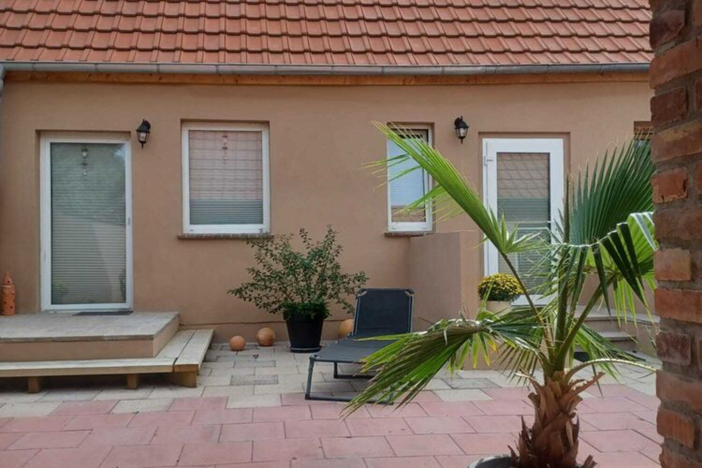 A building with a tiled roof, a bench, a chair, and potted plants.