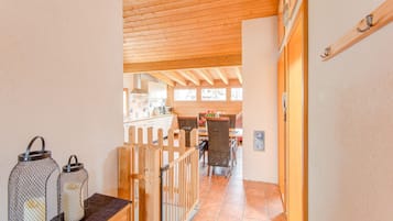 A wooden interior with a kitchen area, dining table, and chairs.