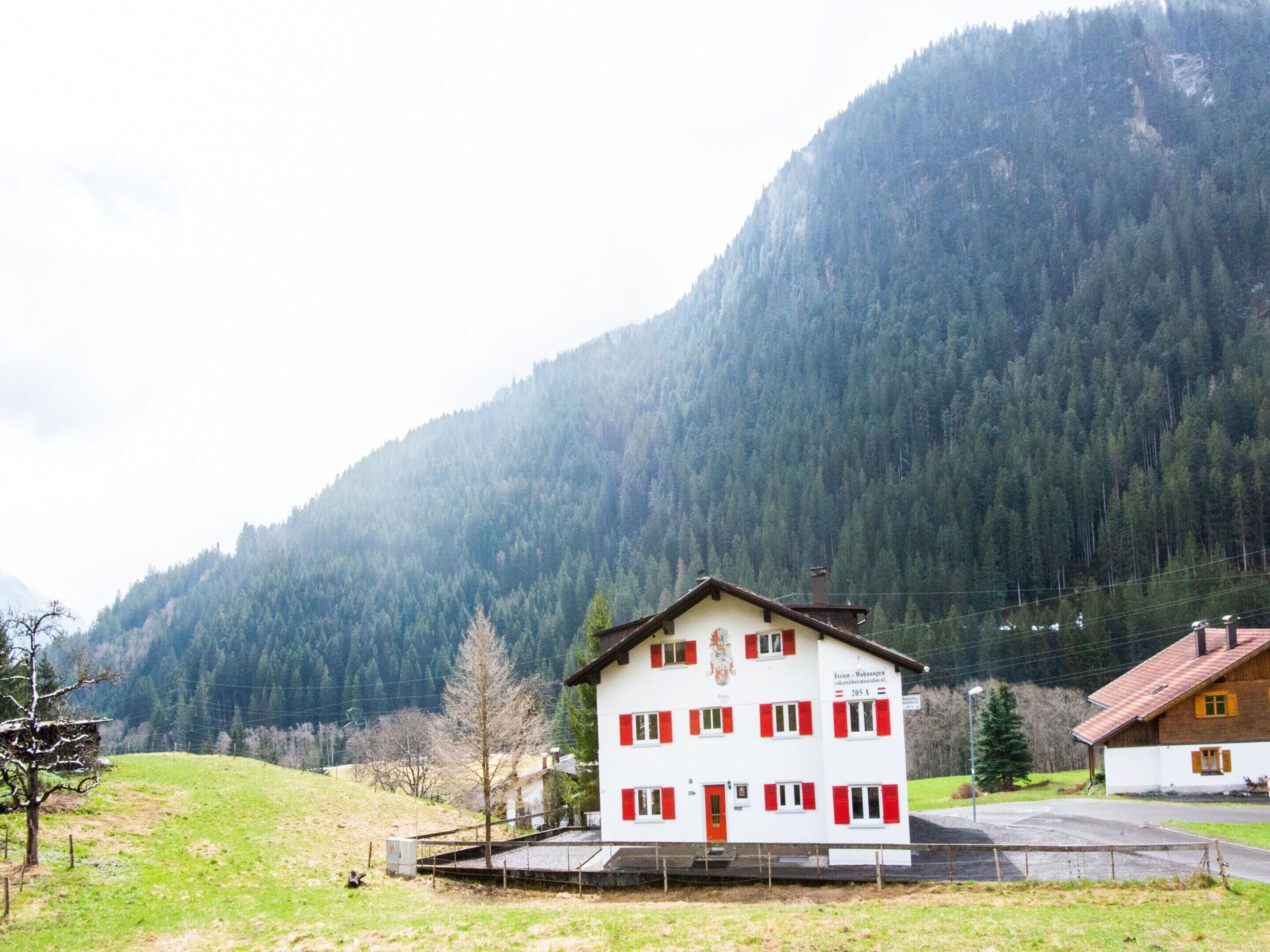 A two-story building with a red and white facade, located in a mountainous area with a forested backdrop.