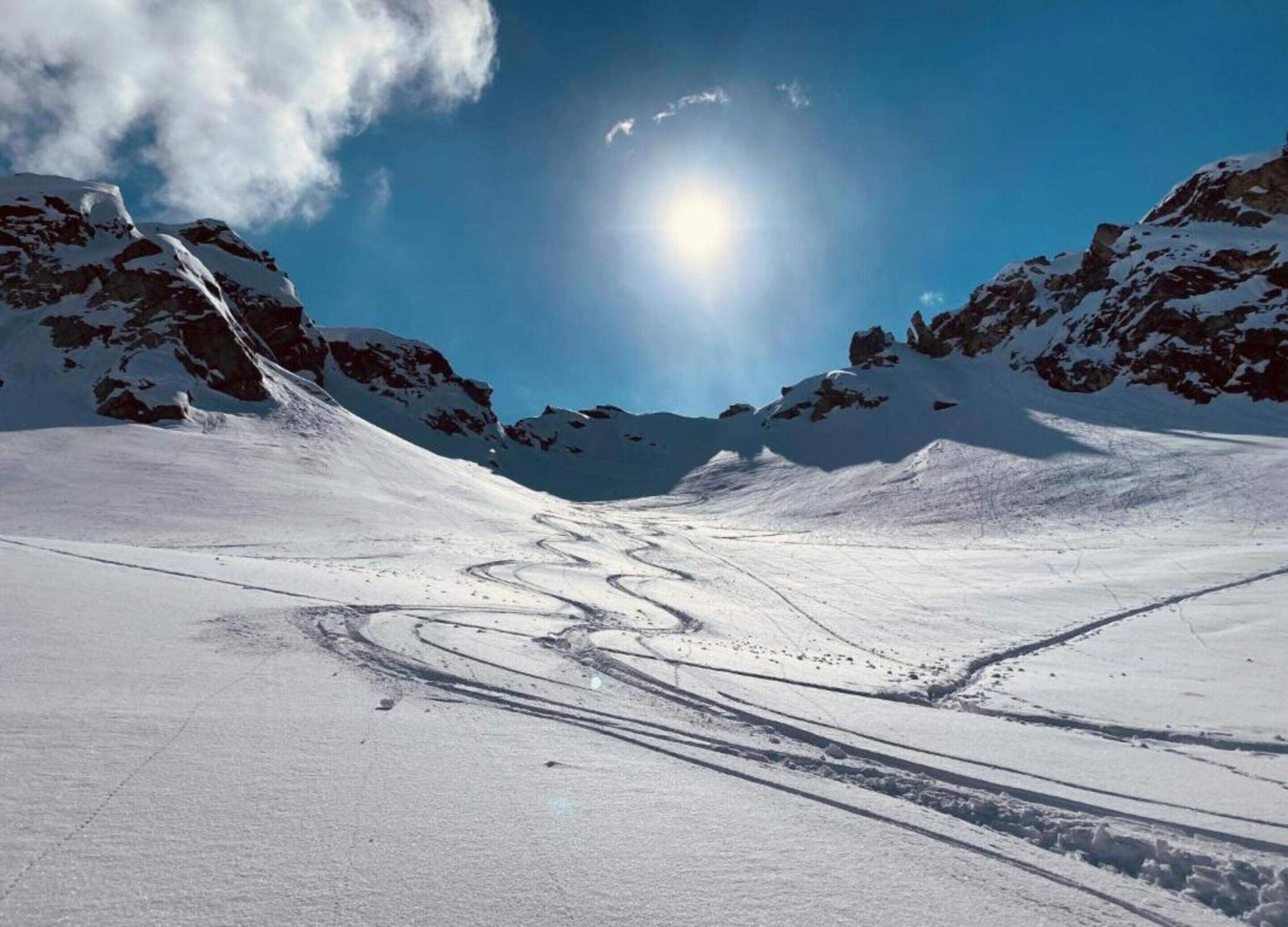 Un paysage de montagne enneigé, avec un ciel dégagé et un soleil brillant.
