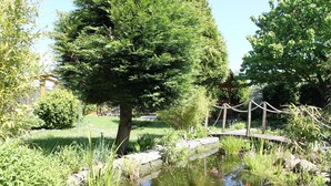 Un jardin paisible avec un étang, un pont en bois et une végétation luxuriante.