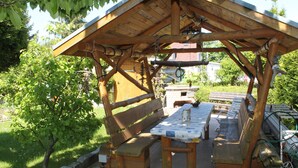 Un pavillon en bois, doté de bancs et d’une table de pique-nique, entouré de verdure.