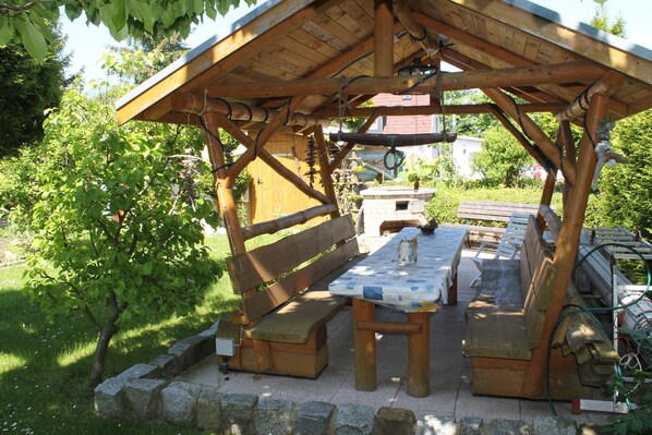 A wooden pavilion with benches and a picnic table, surrounded by greenery. - Comfortable Apartment Near Seabeach in Rerik (Rerik)
