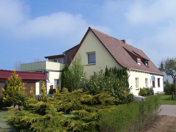 A two-story house with a sloped roof, a balcony, and a well-maintained garden. - Comfortable Apartment Near Seabeach in Rerik (Rerik)