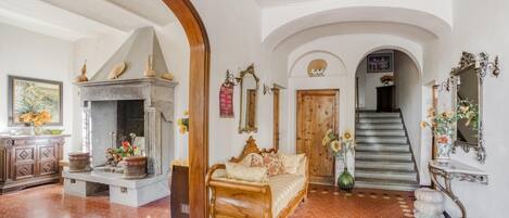 A spacious room with a fireplace, a sofa, and a staircase leading to another area.