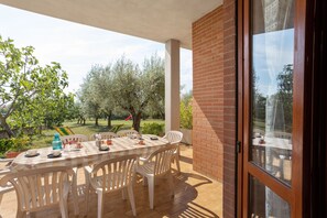 Eine Terrasse mit Tisch und Stühlen, eine Ziegelwand und eine Glastür.