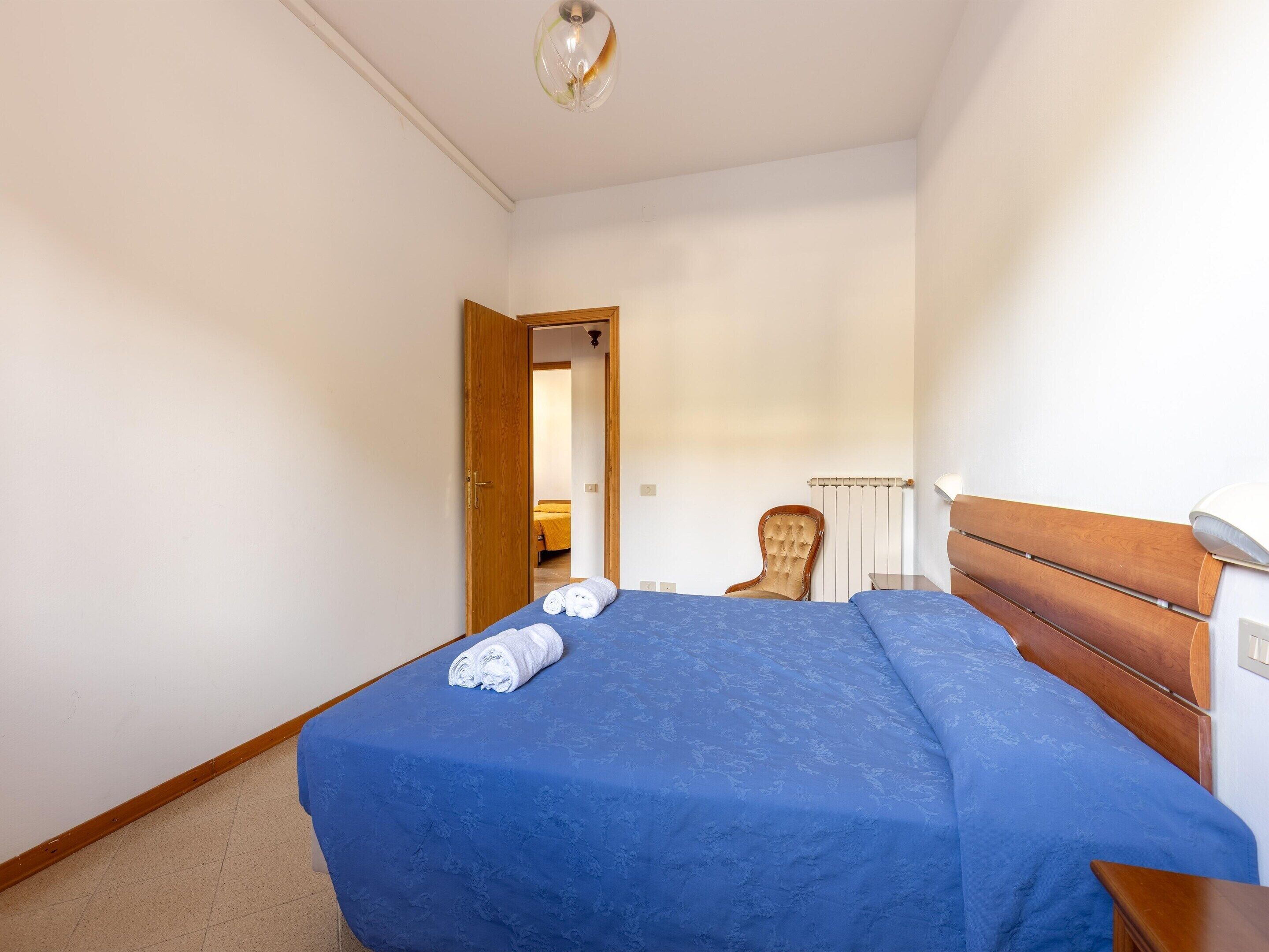 A bedroom with a bed, a wooden headboard, a chair, and a radiator.