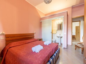 A bedroom with a large bed, a bedside table, a nightstand, a bathroom with a sink and toilet, and a mirror. - Cozy Apartment With Swimming Pool and gym on Lake Trasimeno (Tuoro sul Trasimeno)