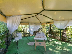 A spa area with a massage table, a chair, and a small table with bottles. - Cozy Apartment With Swimming Pool and gym on Lake Trasimeno (Tuoro sul Trasimeno)