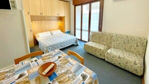 A compact room with a bed, a sofa, and a table with a remote control. - Lovely Holiday Home in Porto Santa Margherita With Pool (Caorle)