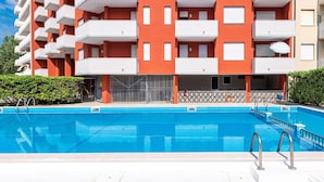 A multi-story building with balconies and a swimming pool in front. - Lovely Holiday Home in Porto Santa Margherita With Pool (Caorle)