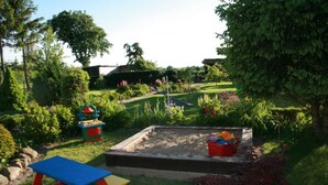 A garden with a sandbox, colorful play structures, and a picnic table. - Beautiful Apartment in Robertsdorf With Garden (Blowatz)
