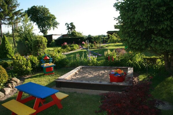A garden with a sandbox, colorful play structures, and a picnic table. - Beautiful Apartment in Robertsdorf With Garden (Blowatz)