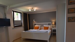A bedroom with a bed, bedside table, lamp, and a TV on the wall. - Beautiful Apartment in Robertsdorf With Garden (Blowatz)