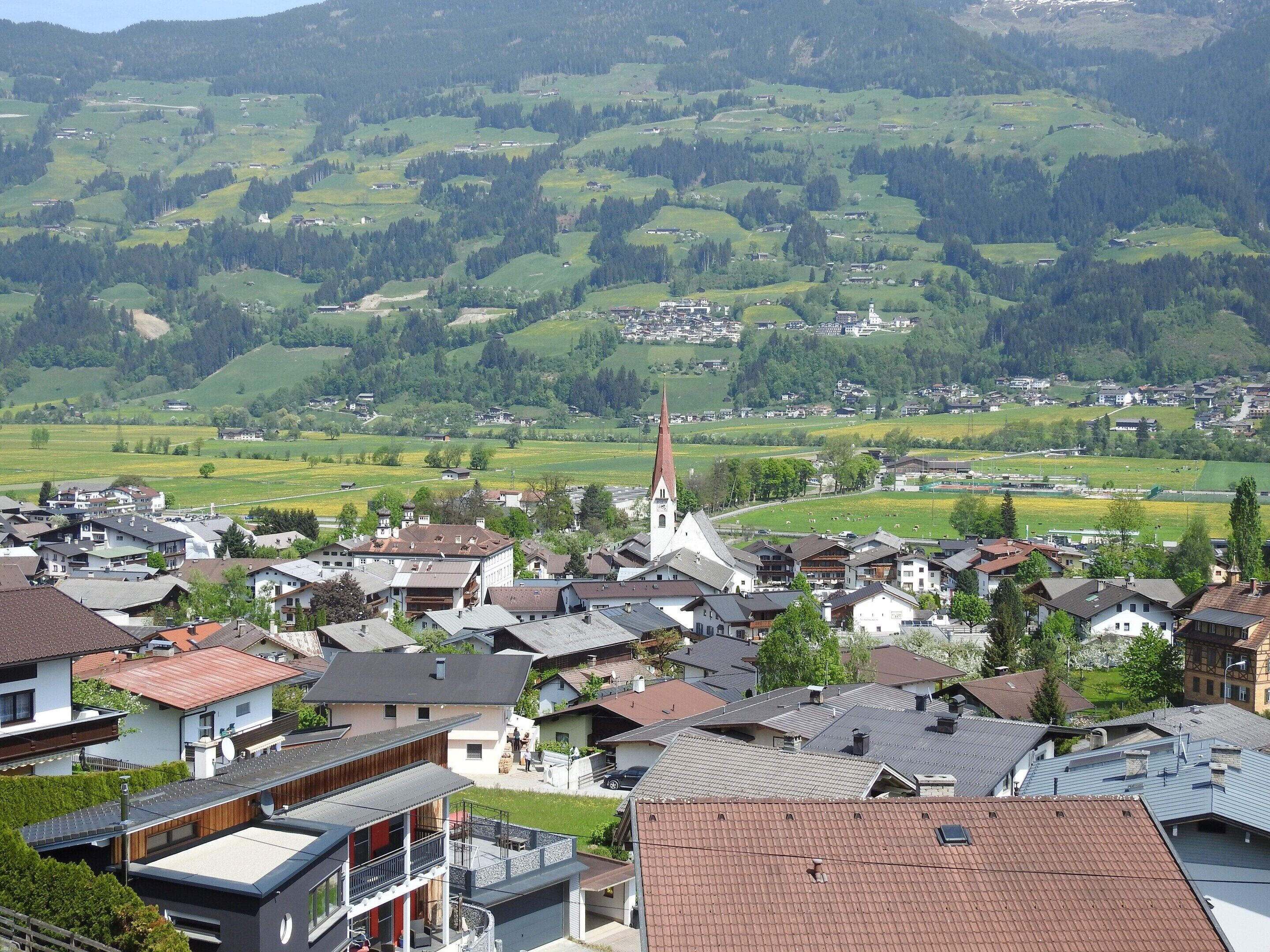 Eine Stadt mit einem markanten Kirchturm, umgeben von Wohngebäuden und grünen Feldern.