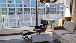 A modern living room with a sofa, a black leather chair, a small table, and a glass partition. - Modern Apartment in Oostende With Terrace (Ostend)