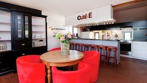 Una cocina moderna con barra, taburetes rojos y una mesa de comedor con sillas rojas.