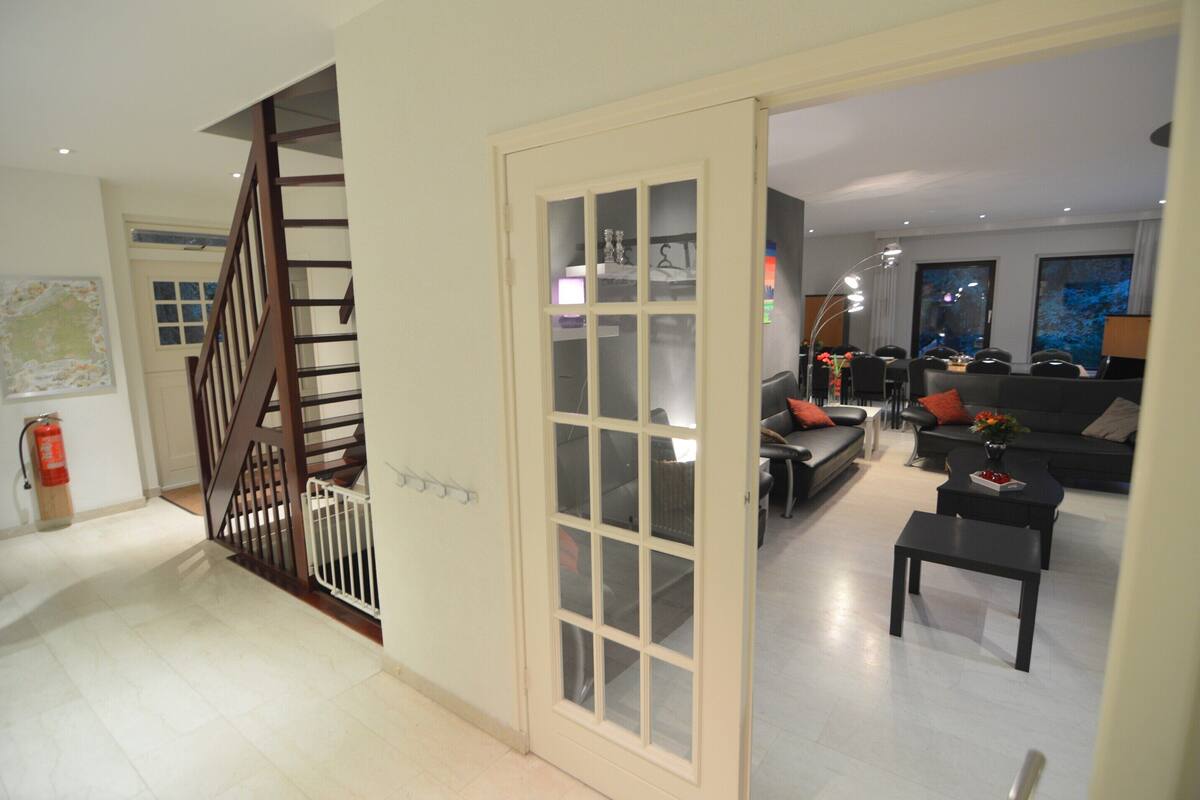 A modern living area with a staircase, a dining area, and a sofa set.