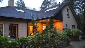 Ein zweistöckiges Haus mit Backsteinfassade, geneigtem Dach und erkennbarem Schornstein.