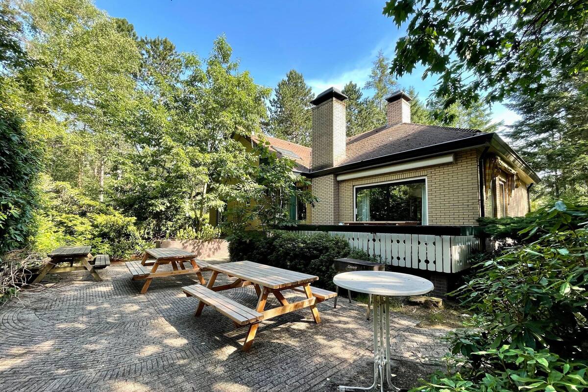 A rustic cabin with a brick exterior, surrounded by dense greenery and a wooden deck.