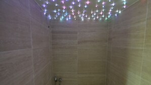 Un baño revestido con azulejos, con ducha y manguera.